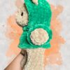 Tan crochet bear plushie in a green hoodie - left view