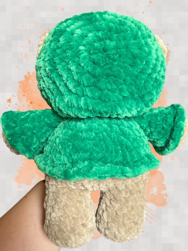 Tan crochet bear plushie in a green hoodie - back view